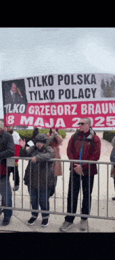 a group of people standing behind a fence with a sign that says " tylko polska tylko polacy "