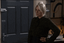 a woman wearing a leopard print shirt is standing in front of a door