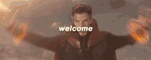 a man in a cloak is standing on a rocky hill with the words `` welcome '' written above him .