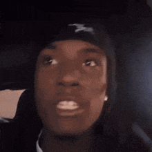 a man wearing a black beanie with the letter s on it looks at the camera