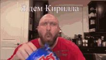 a bald man in a red shirt is eating a bag of chips with a foreign language written on it