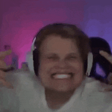 a man wearing headphones is smiling in front of a pink background .