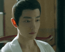 a close up of a man 's face with a ponytail on his head