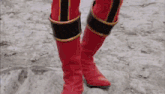 a person wearing red boots is standing on a rocky surface .