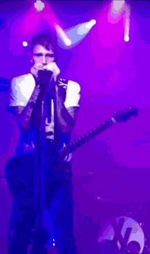 a man playing a guitar and singing into a microphone
