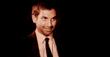 a man in a suit and tie is smiling while looking at the camera .