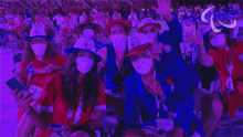a group of people wearing face masks are sitting in a crowd at a sports event