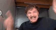 a man with a mustache is making a funny face while sitting in front of a mirror .