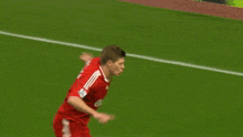 a soccer player in a red jersey is jumping in the air on the field