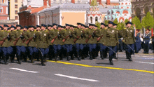 a group of soldiers march down a street in front of buildings