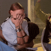 a woman is covering her face with her hands while a man holds her