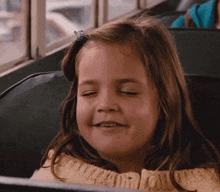 a little girl is sitting on a bus with her eyes closed .