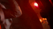 a person is standing in a dark room with a red light coming out of the door .
