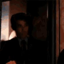 a man in a suit and tie is standing in a doorway looking out the window .