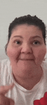a woman is making a funny face while wearing a white shirt .