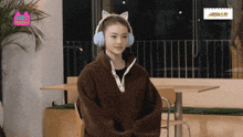 a woman wearing a cat ear headband is sitting at a table in front of a sign that says aridie