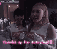 two girls are giving thumbs up for everyone while standing next to each other