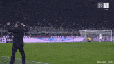 a man stands on a soccer field in front of an ad for qatar airlines