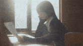 a woman is sitting at a desk looking at a piece of paper .