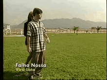 a man and woman are standing in a grassy field with the name falha nossa vira-lata