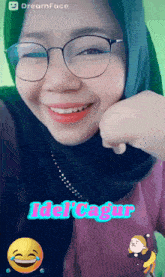 a woman wearing glasses and a hijab is smiling with the words idol cagur written above her