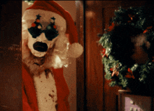a clown dressed as santa claus is standing in a doorway