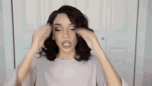 a woman is holding her hair in front of a white door .