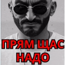 a man with a beard wearing sunglasses and a white shirt with the words " прям щас надо " in red letters