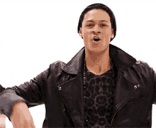 a man wearing a leather jacket and a leopard print shirt is making a funny face