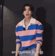 a young man wearing a pink and blue striped shirt is screaming .