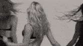 a black and white photo of three women in lingerie dancing .