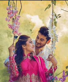 a man and woman are sitting on a swing with flowers .