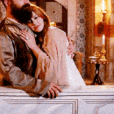 a man with a beard is hugging a woman with red hair