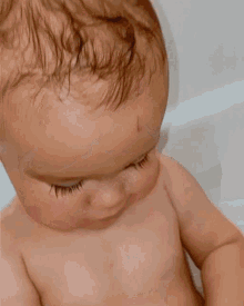 a baby is taking a bath and looking at the camera .