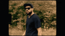 a man wearing sunglasses and a hat is standing in a field
