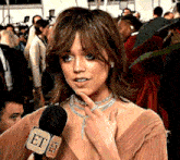 a woman is talking into a microphone that says et