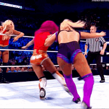 a female wrestler in a red top is fighting another wrestler in a purple outfit