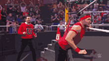 a man in a red tank top is holding a trophy in front of a crowd with the letters w on it