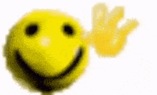 a close up of a yellow smiley face with a hand waving .