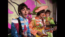 a group of men in military uniforms are playing guitars and singing on a stage