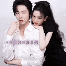 a man and a woman are posing for a picture with chinese writing on the wall behind them