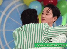 two men in striped shirts are hugging each other .