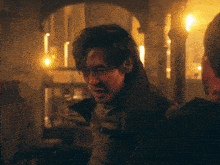 a man in a dark room with candles on the walls