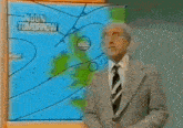 a man in a suit and tie stands in front of a screen that says pressure at 6pm