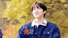 a young man wearing a blue jacket with chinese writing on it smiles for the camera