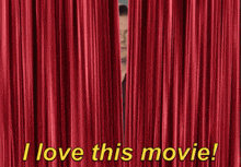 a man stands in front of a red curtain that says " i love this movie "