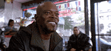 a man in a leather jacket smiles in front of a window with a sign that says ' chinese restaurant ' on it