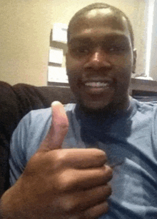a man in a blue shirt is giving a thumbs up sign