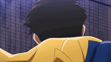 a man in a yellow jacket is standing in front of a wall