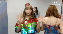a group of girls are standing next to each other in a room and one of them is waving at the camera .
